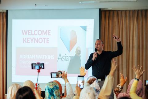 Adrian Watkins delivering an industry welcome keynote with audience visible.