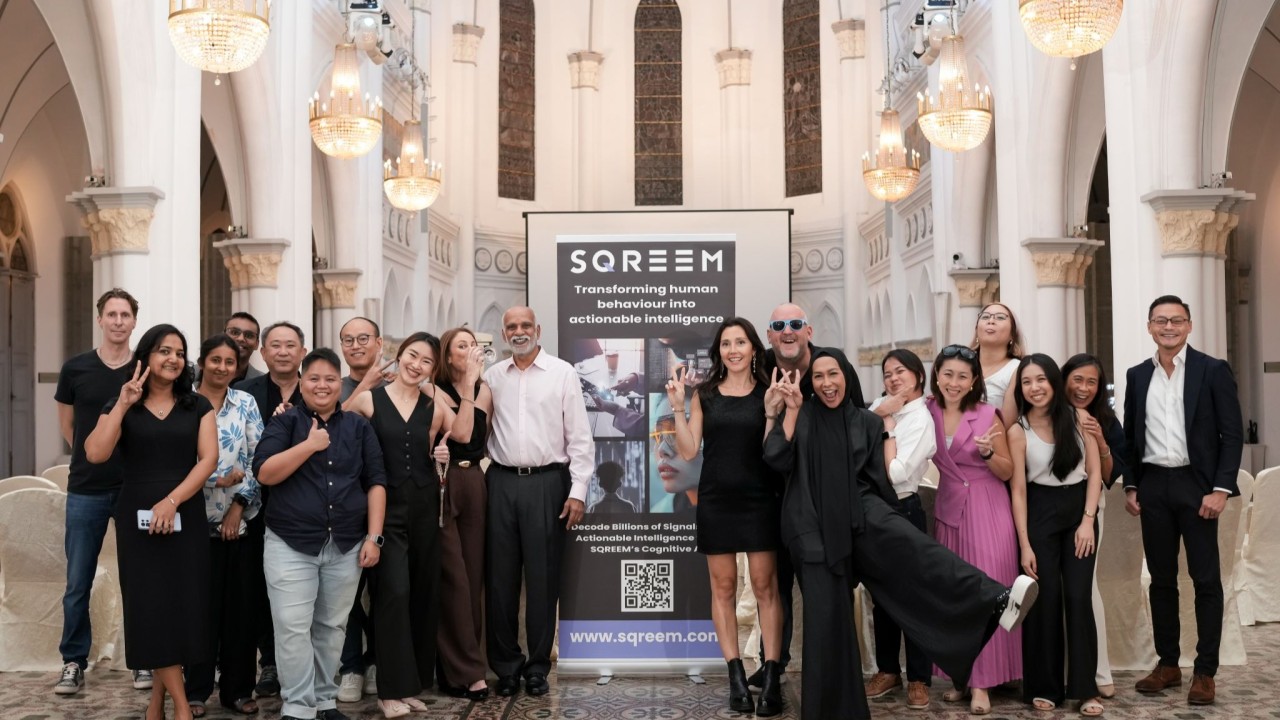 Adrian Watkins with the SQREEM Technologies team in front of a SQREEM banner.